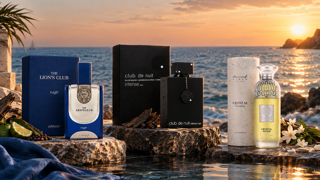 Luxury perfume collection featuring The Lion’s Club, Club de Nuit Intense Man, and Crystal Morning perfumes displayed by the sea at sunset.