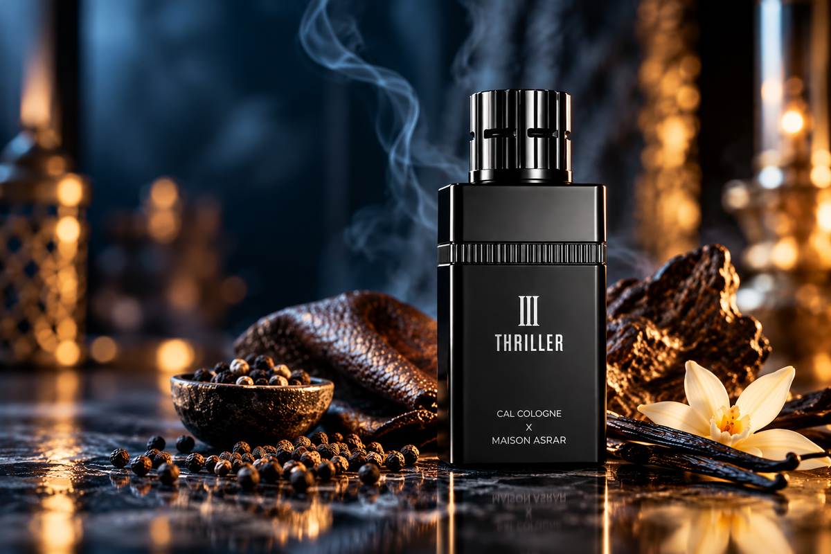 Maison Asrar Thriller III Cal Cologne perfume in a sleek black bottle, styled with dark wood, peppercorns, vanilla flower and atmospheric smoke against a luxurious blue and golden background.